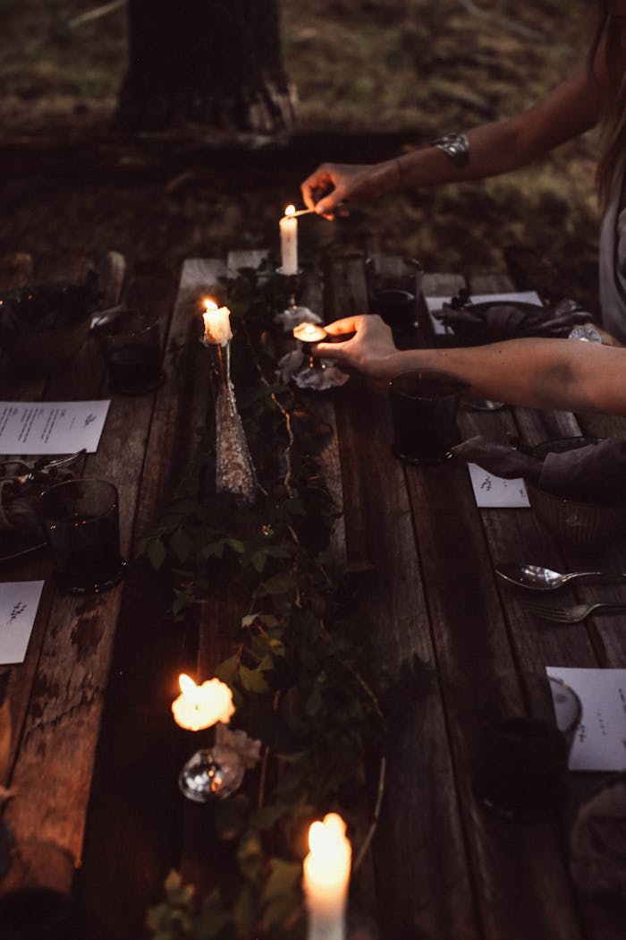 Crop women burning candles on banquet table